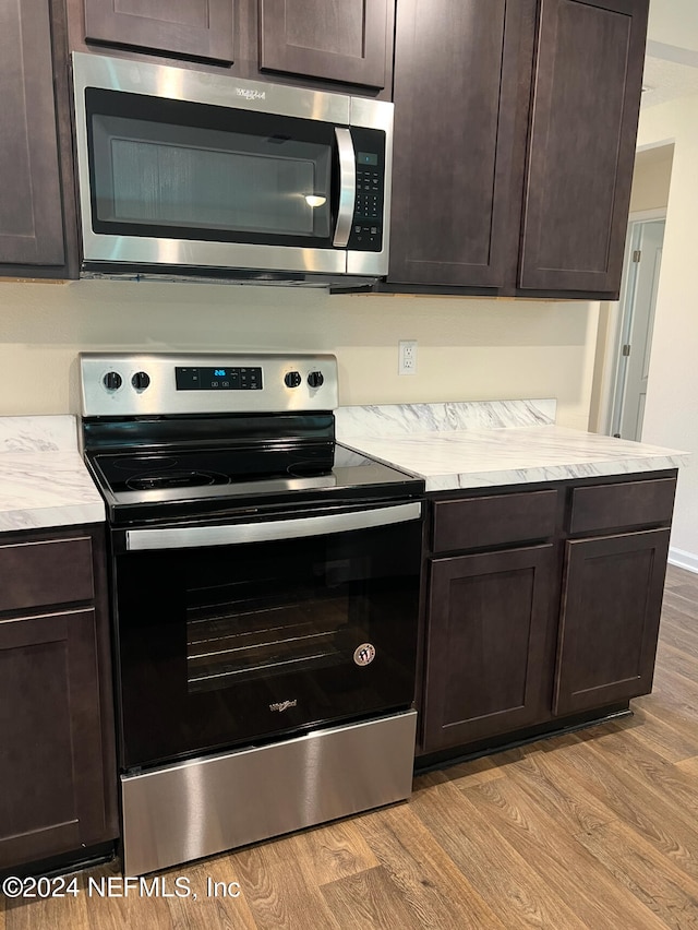 kitchen with dark brown cabinets, stainless steel appliances, and light hardwood / wood-style floors