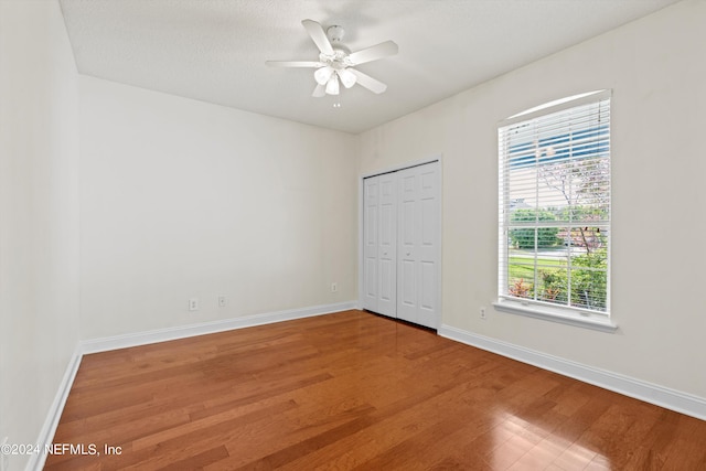 unfurnished bedroom featuring a closet, ceiling fan, hardwood / wood-style flooring, and a textured ceiling