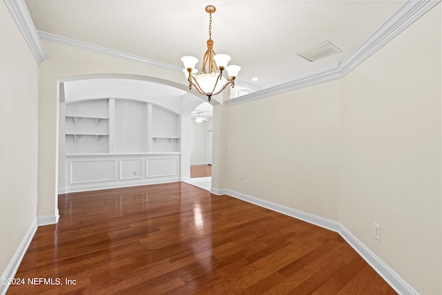 unfurnished dining area featuring built in features, ornamental molding, a textured ceiling, an inviting chandelier, and dark hardwood / wood-style flooring