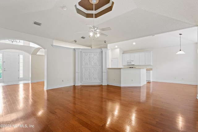 unfurnished living room featuring light wood-type flooring, a textured ceiling, and vaulted ceiling