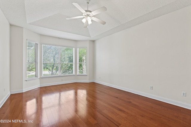 empty room with a textured ceiling, wood-type flooring, and plenty of natural light