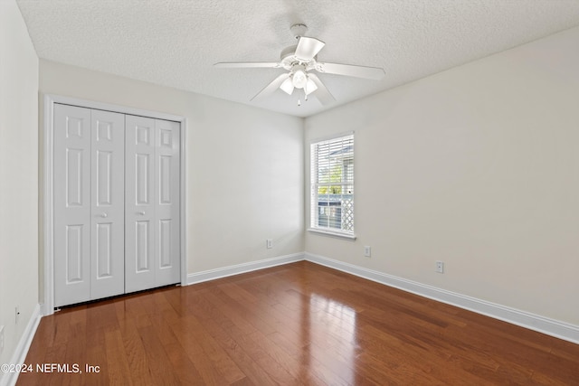 unfurnished bedroom with a textured ceiling, hardwood / wood-style floors, ceiling fan, and a closet