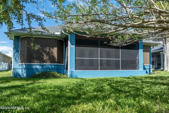 view of side of property featuring a sunroom and a yard