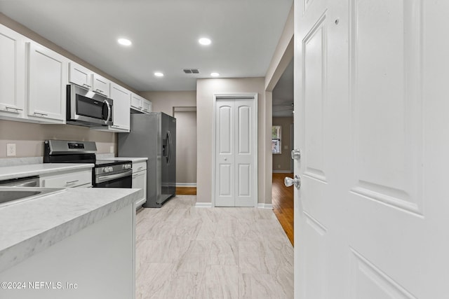 kitchen with white cabinets, stainless steel appliances, and light hardwood / wood-style floors