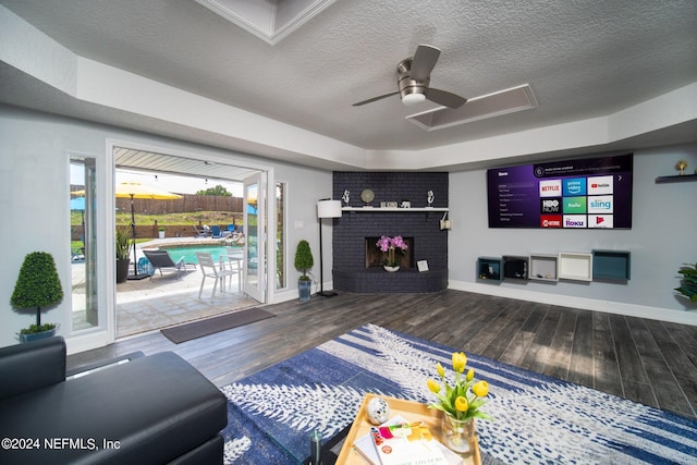 living room featuring a fireplace, ceiling fan, plenty of natural light, and dark wood-type flooring