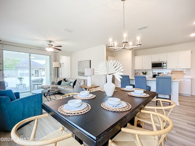 dining space with ceiling fan with notable chandelier and light wood-type flooring