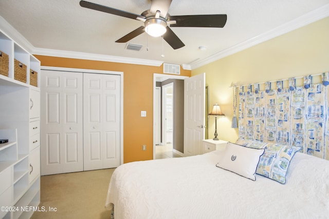 bedroom featuring ceiling fan, light colored carpet, a closet, and ornamental molding