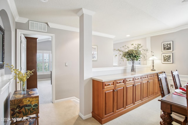 kitchen featuring a textured ceiling, ornamental molding, and light carpet