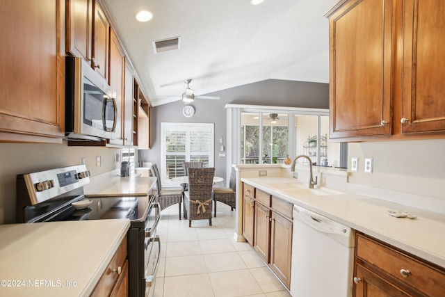 kitchen featuring light tile patterned flooring, vaulted ceiling, stainless steel appliances, ceiling fan, and sink