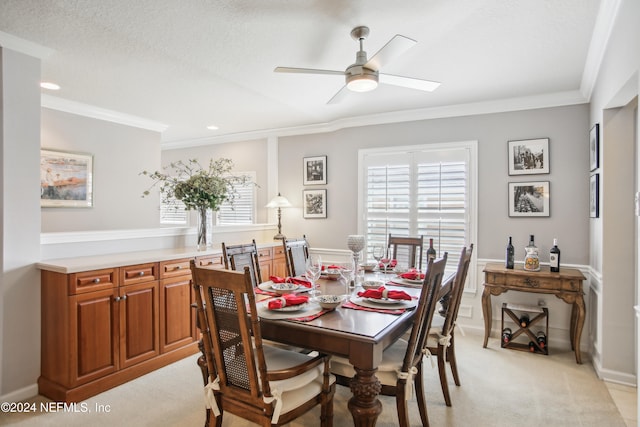 carpeted dining room with a textured ceiling, ornamental molding, and ceiling fan