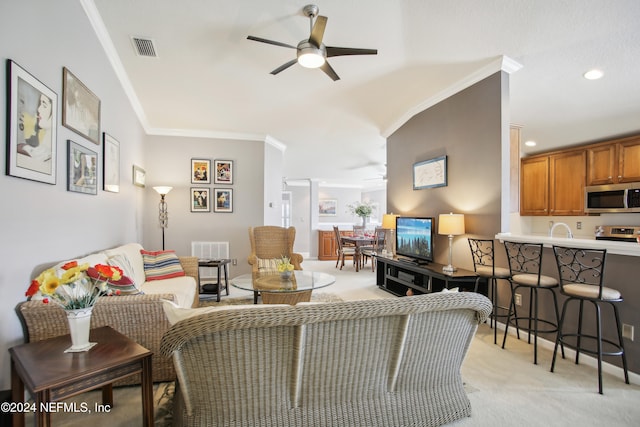 carpeted living room with ceiling fan, sink, and ornamental molding