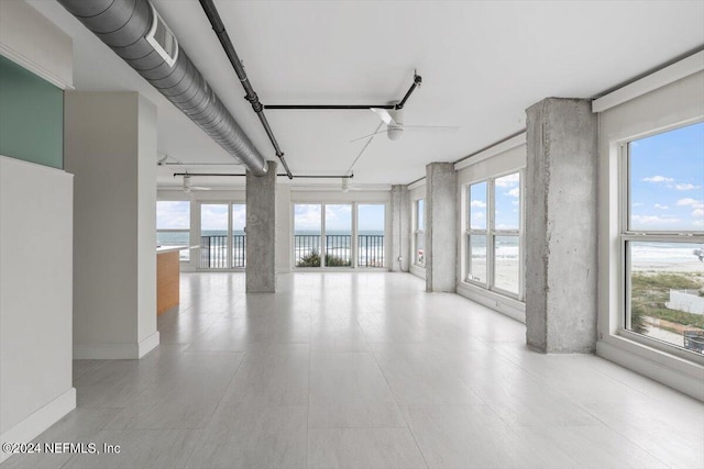 empty room featuring ceiling fan, plenty of natural light, and a water view