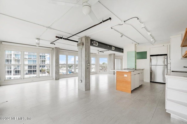 kitchen featuring white cabinetry, stainless steel fridge, a kitchen island, and a healthy amount of sunlight