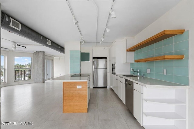 kitchen with a center island, sink, decorative backsplash, appliances with stainless steel finishes, and white cabinetry