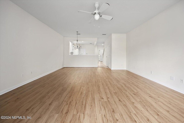 unfurnished living room with ceiling fan with notable chandelier and light hardwood / wood-style flooring