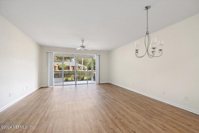 spare room with hardwood / wood-style flooring and ceiling fan with notable chandelier