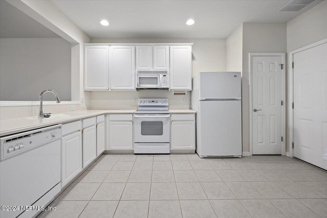 kitchen with white appliances, light tile patterned flooring, sink, and white cabinets