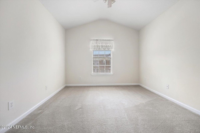 carpeted empty room featuring vaulted ceiling