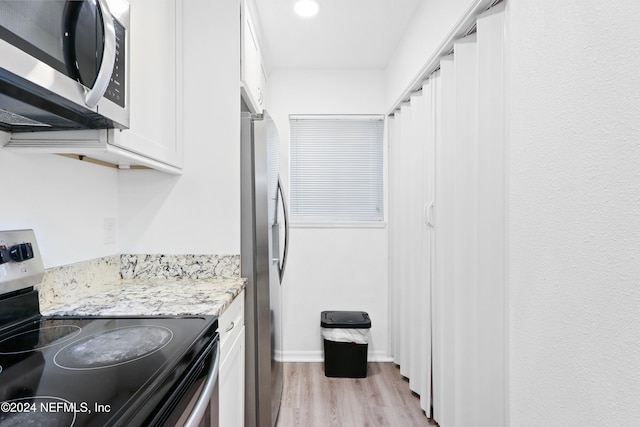 kitchen featuring stainless steel appliances, white cabinetry, light wood-style flooring, and light stone countertops