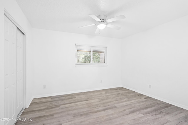 unfurnished bedroom featuring light wood-type flooring, baseboards, and a closet