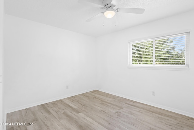 empty room featuring light wood finished floors, a ceiling fan, and baseboards