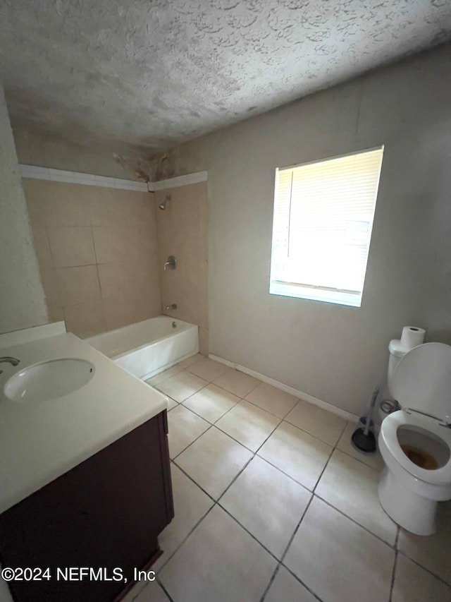 full bathroom featuring tile patterned flooring, a textured ceiling, vanity, tiled shower / bath, and toilet