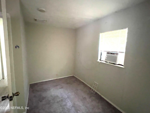 unfurnished room featuring cooling unit and dark colored carpet