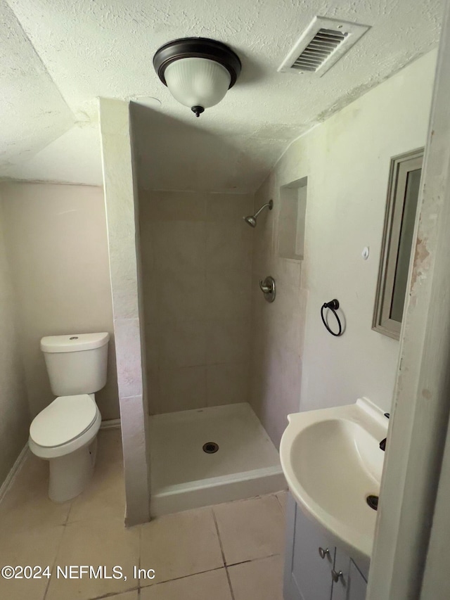 bathroom featuring vanity, tile patterned flooring, toilet, and tiled shower