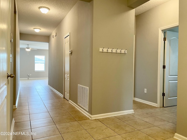 hallway featuring light tile patterned flooring and a textured ceiling