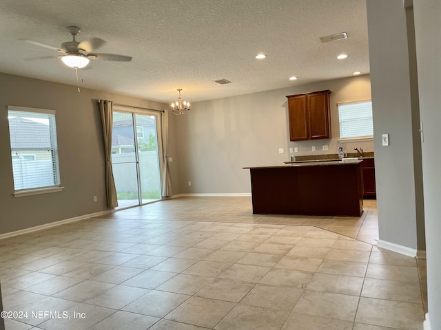 kitchen featuring ceiling fan with notable chandelier, sink, hanging light fixtures, light tile patterned floors, and a textured ceiling