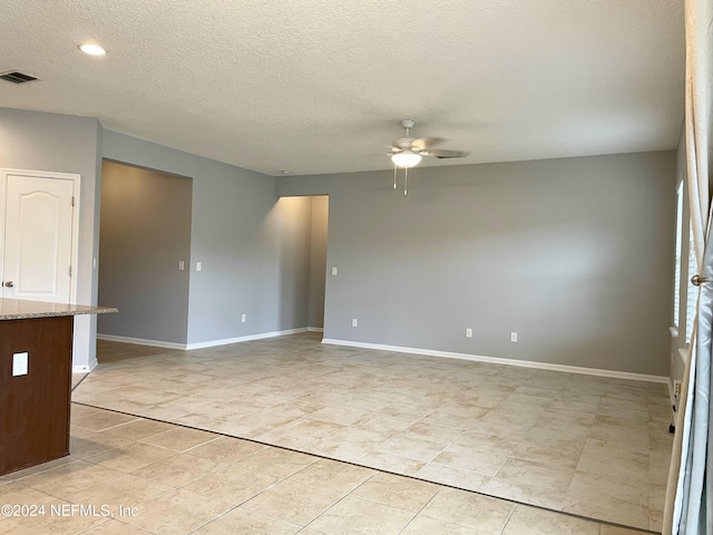 empty room with a textured ceiling and ceiling fan