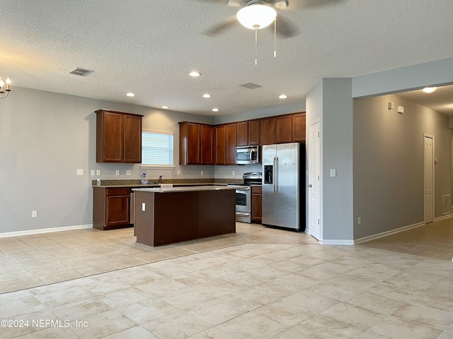 kitchen featuring ceiling fan with notable chandelier, sink, a textured ceiling, a kitchen island, and stainless steel appliances