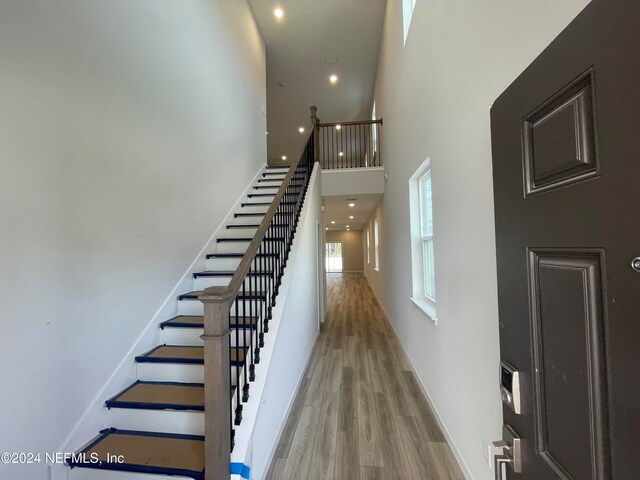 stairs with a towering ceiling and hardwood / wood-style flooring