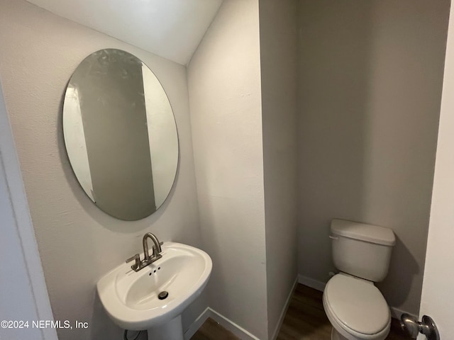 bathroom featuring toilet, hardwood / wood-style flooring, sink, and vaulted ceiling