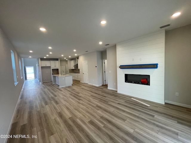 unfurnished living room featuring light wood-type flooring, a fireplace, and sink