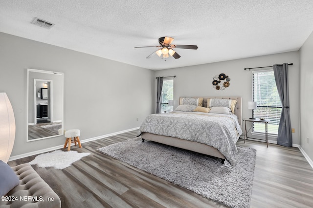 bedroom with a textured ceiling, hardwood / wood-style floors, and ceiling fan