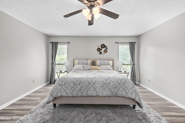 bedroom featuring multiple windows, dark hardwood / wood-style floors, and ceiling fan