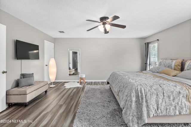 bedroom with ceiling fan, hardwood / wood-style floors, and a textured ceiling