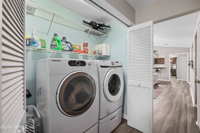 washroom featuring wood-type flooring, a textured ceiling, and washing machine and clothes dryer