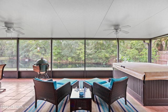 sunroom featuring a water view and ceiling fan