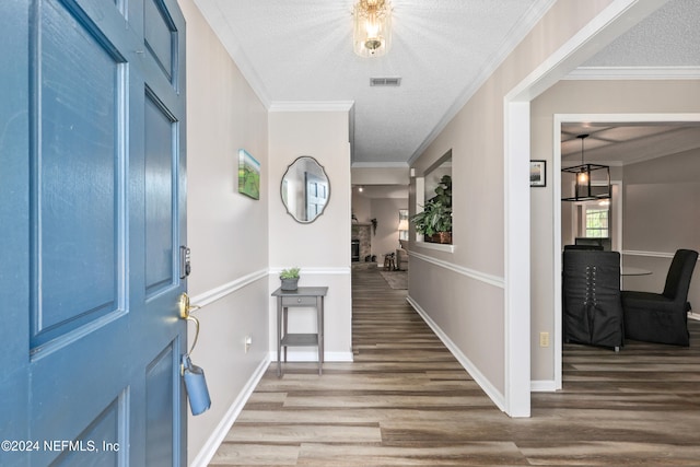 entryway featuring a textured ceiling, crown molding, and hardwood / wood-style floors