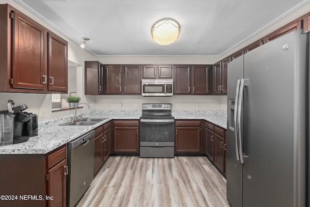 kitchen featuring appliances with stainless steel finishes, light hardwood / wood-style floors, light stone countertops, dark brown cabinets, and sink