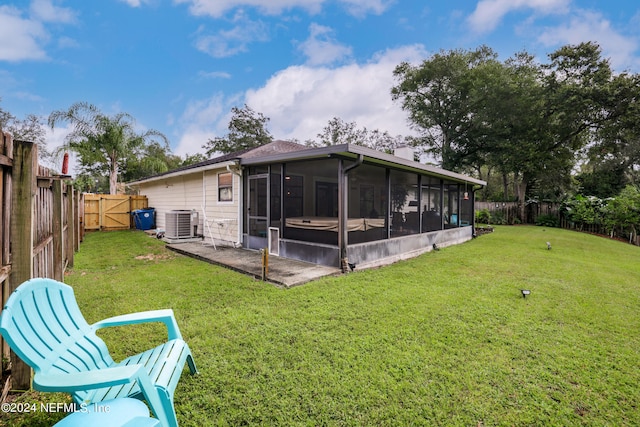 back of property featuring a lawn, a sunroom, and central AC unit