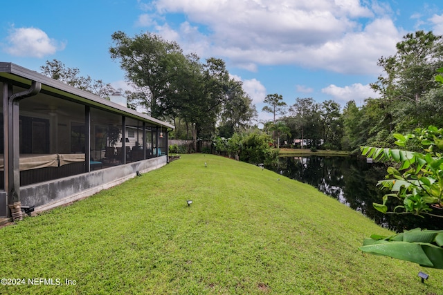 view of yard with a sunroom and a water view