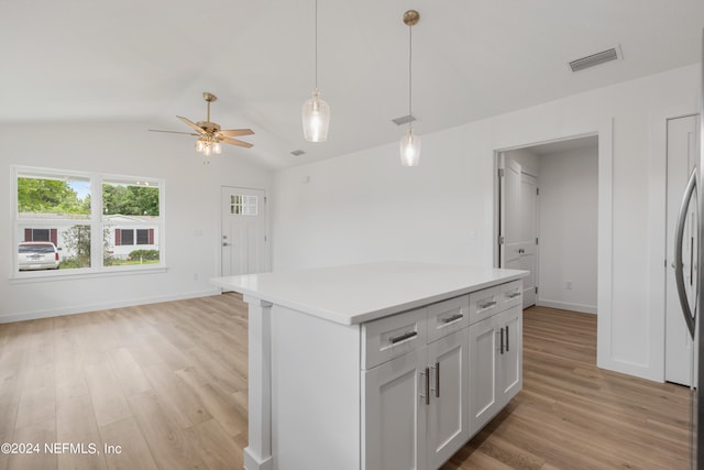 kitchen with light wood-type flooring, lofted ceiling, white cabinetry, and pendant lighting