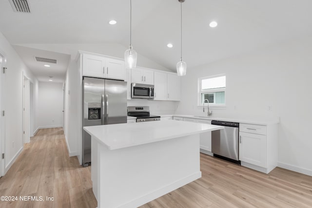 kitchen featuring white cabinets, lofted ceiling, hanging light fixtures, stainless steel appliances, and a center island