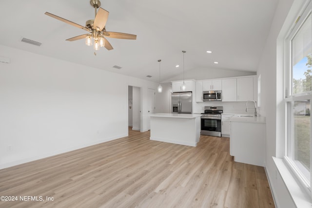 kitchen featuring light wood-type flooring, white cabinets, vaulted ceiling, stainless steel appliances, and decorative light fixtures