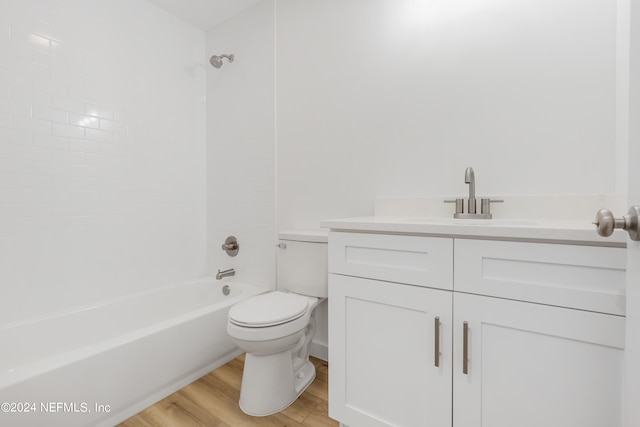 full bathroom with tiled shower / bath combo, vanity, hardwood / wood-style floors, and toilet