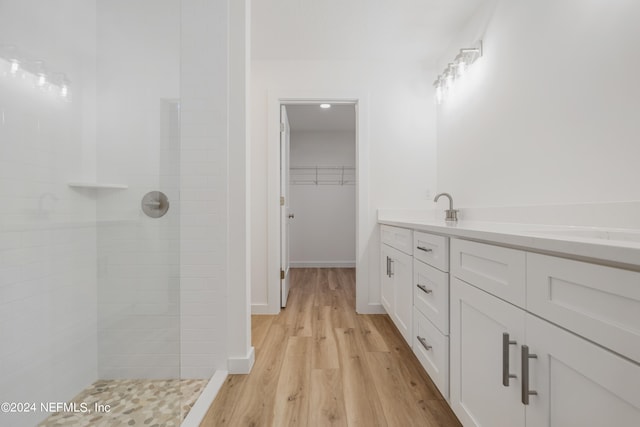 bathroom featuring wood-type flooring, vanity, and a tile shower