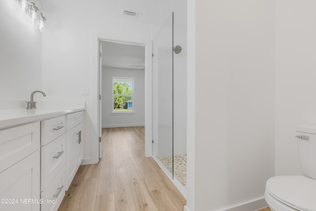 bathroom featuring walk in shower, vanity, toilet, and hardwood / wood-style flooring